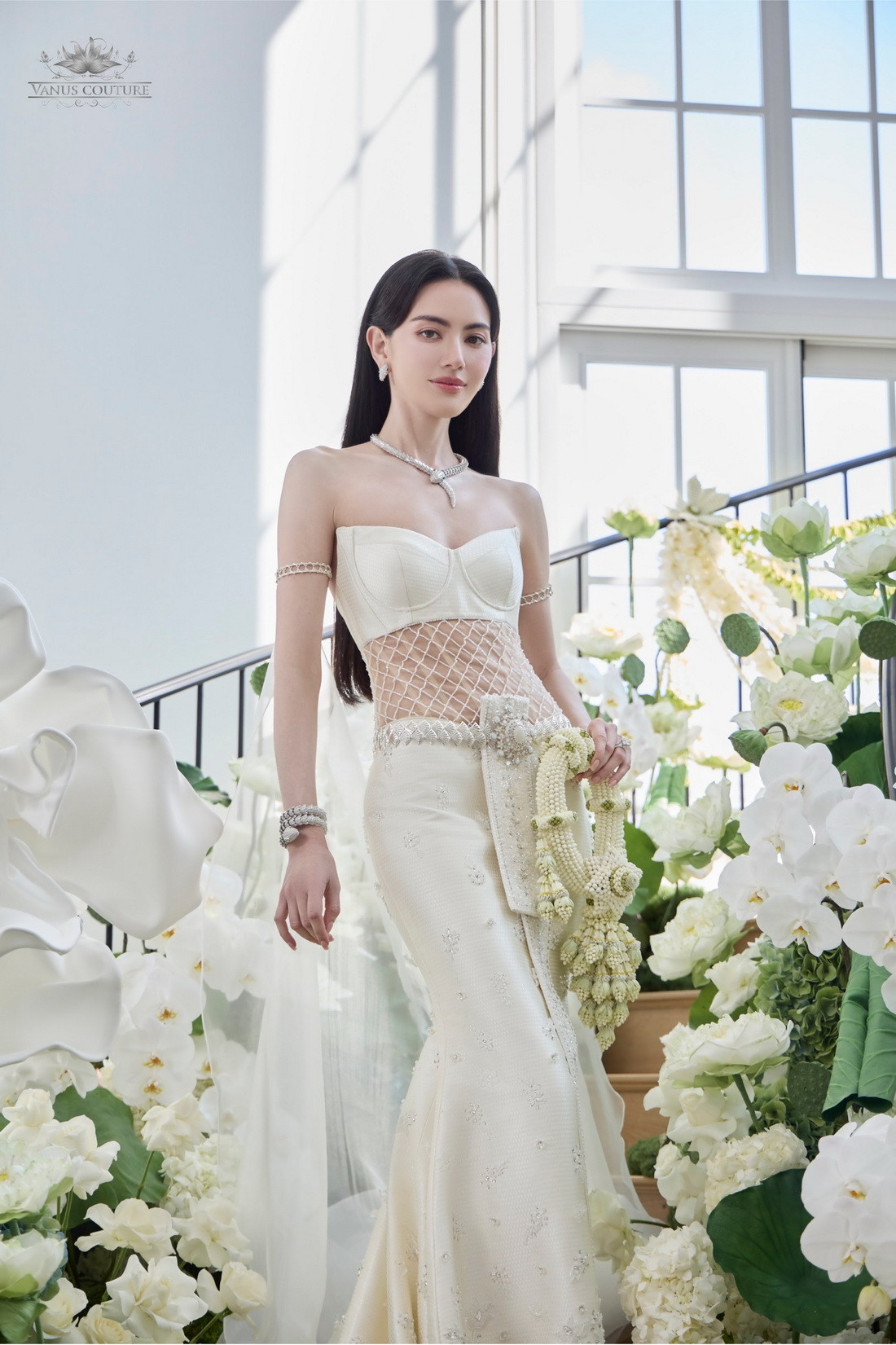 Mai Davika in an ivory adapted Thai bridal dress with a structured bodice, fitted skirt and long flowing fabric from the upper arms.